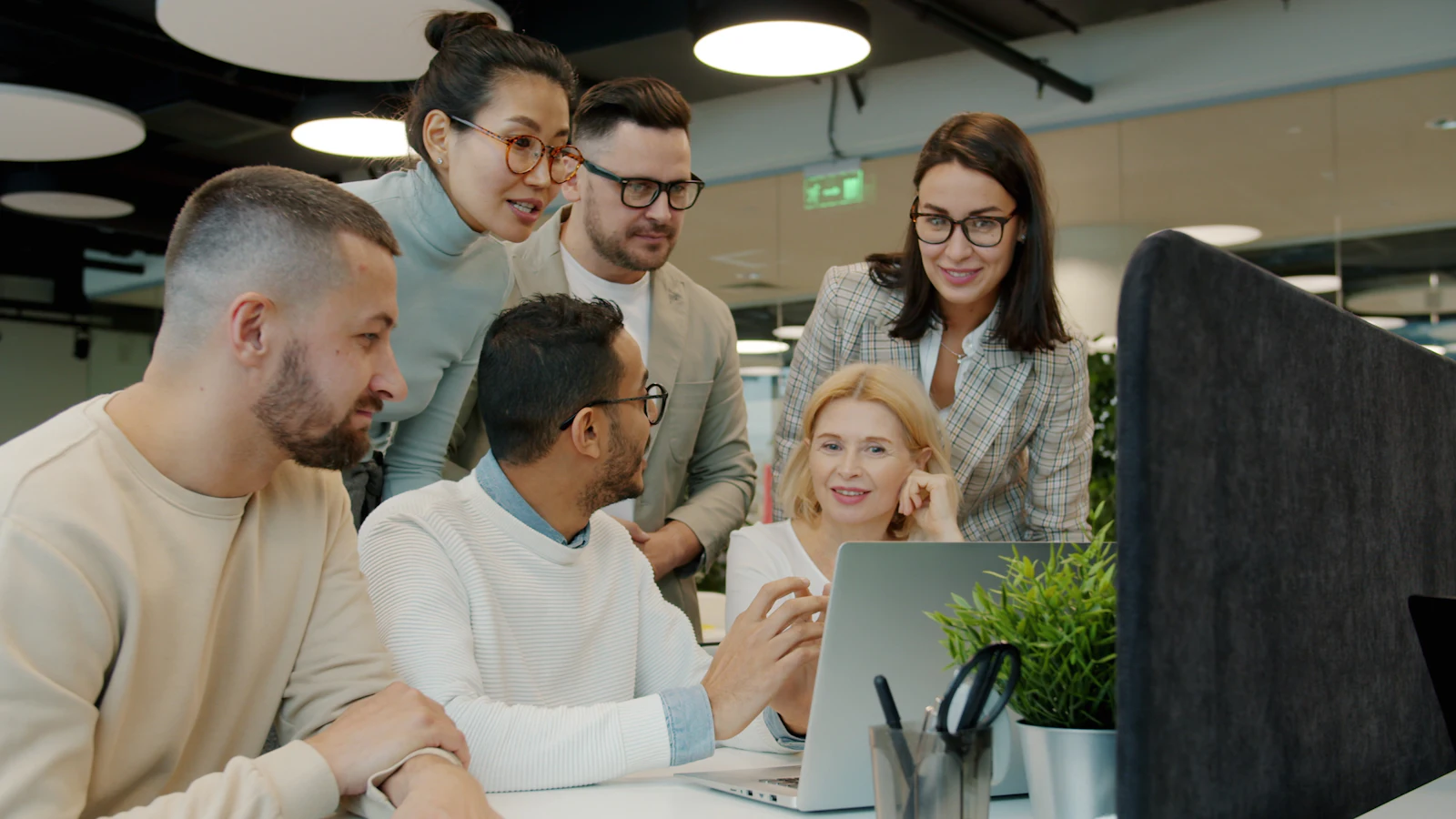 Team arbeitet gemeinsam am Laptop im Großraumbüro