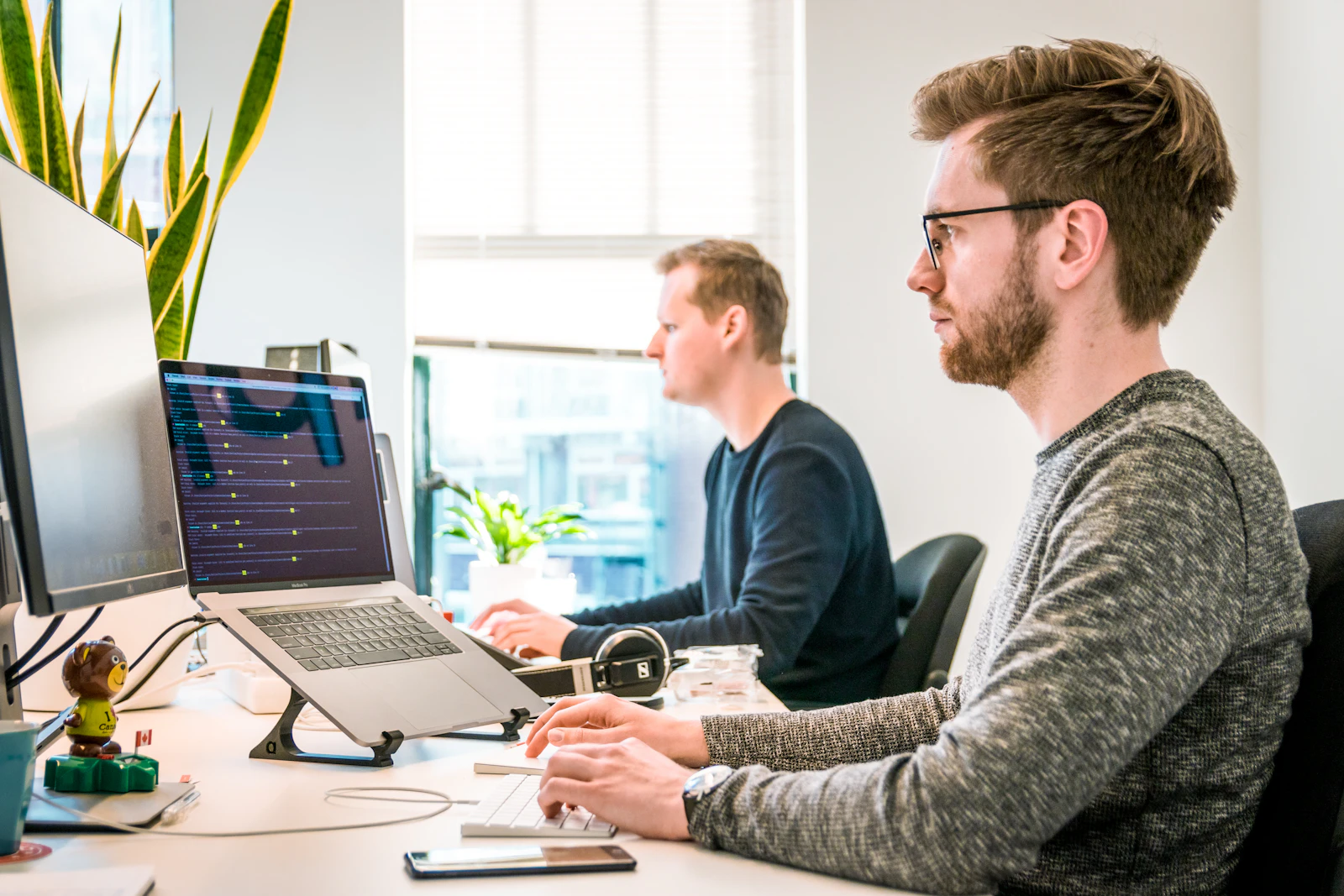 Zwei IT-Mitarbeiter richten an ihren Arbeitsplätzen Laptops ein