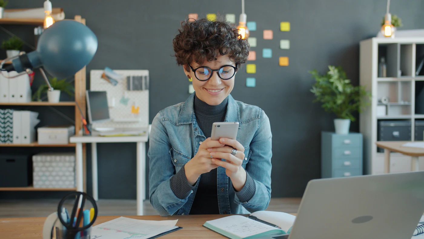 Mitarbeiterin richtet lächelnd ihren Passwortmanager am Smartphone ein