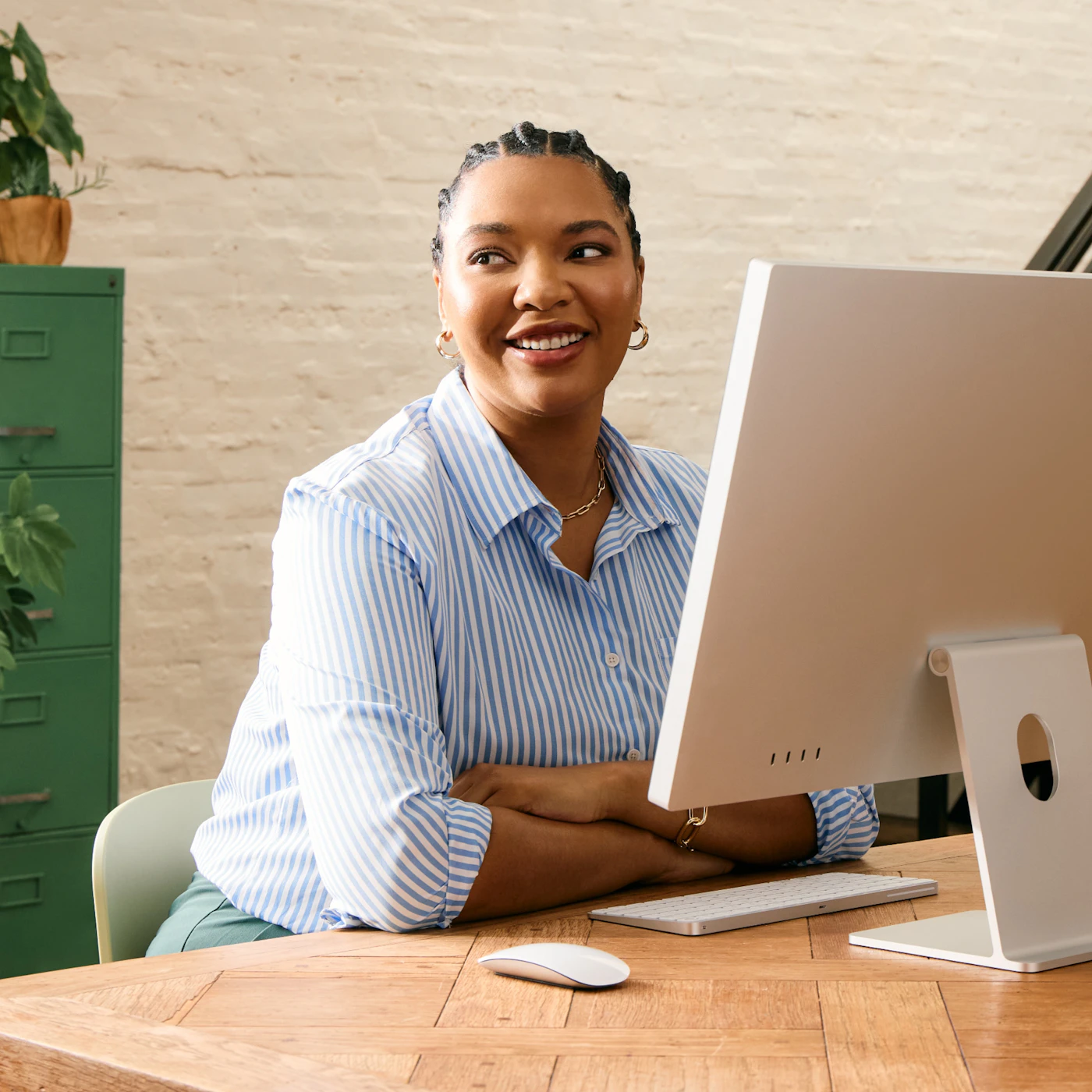 Lächelnde Mitarbeiterin an ihrem neuen Arbeitsplatz mit iMac